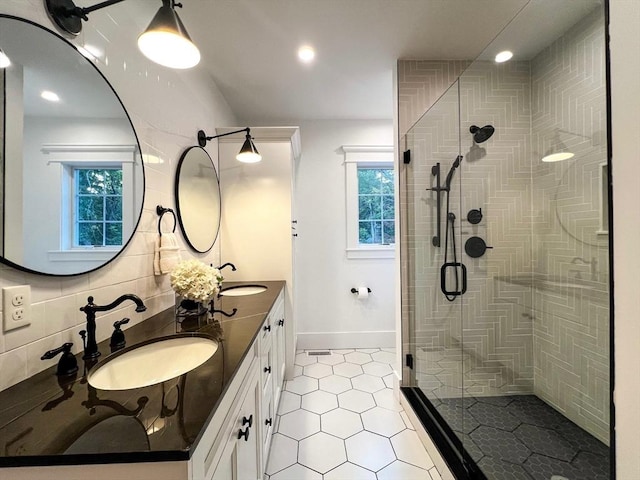 full bathroom featuring a sink, baseboards, a stall shower, and double vanity