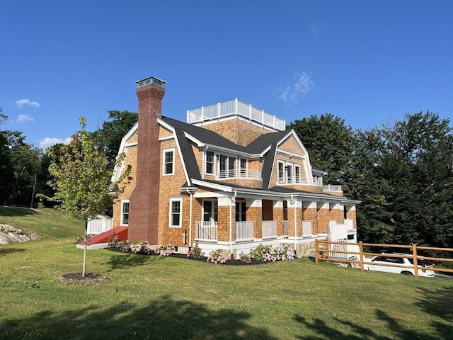 view of front of home featuring a gambrel roof, a shingled roof, a front lawn, and fence