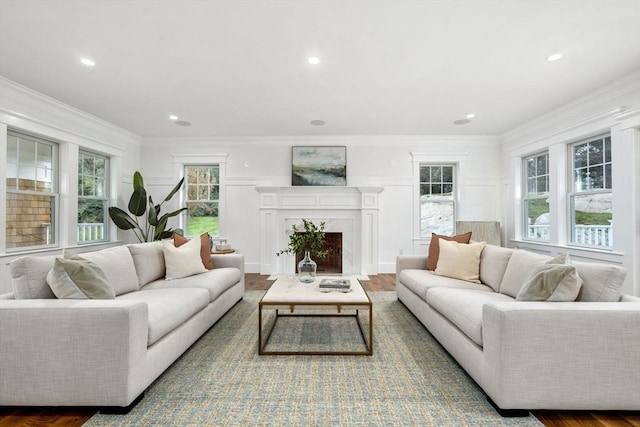 living room featuring a decorative wall, crown molding, and wood finished floors