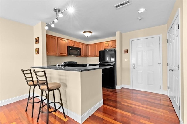 211 Central St Unit A311, Norwood, MA 02062 - kitchen with black appliances, a breakfast bar area, dark wood-style flooring, and a peninsula