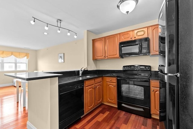 211 Central St Unit A311, Norwood, MA 02062 - kitchen with black appliances, a peninsula, dark wood-style flooring, and brown cabinets