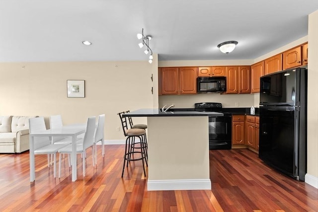 211 Central St Unit A311, Norwood, MA 02062 - kitchen with black appliances, dark countertops, dark wood-style floors, a breakfast bar, and recessed lighting