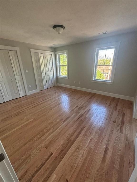 77 Lake Shore Dr, Weymouth, MA 02189 - unfurnished bedroom featuring two closets, baseboards, and wood finished floors