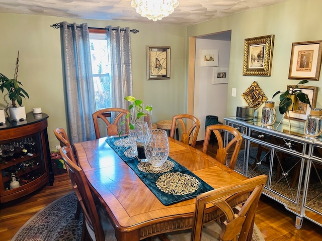 dining space featuring dark hardwood / wood-style flooring, a notable chandelier, and a textured ceiling