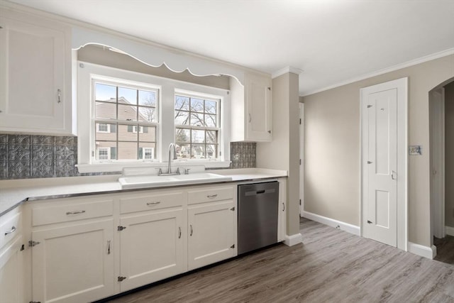 kitchen with ornamental molding, decorative backsplash, stainless steel dishwasher, white cabinetry, and a sink