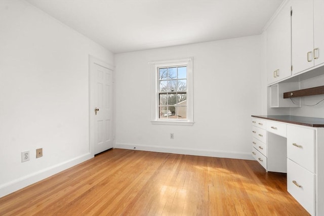 unfurnished office featuring light wood-type flooring and baseboards