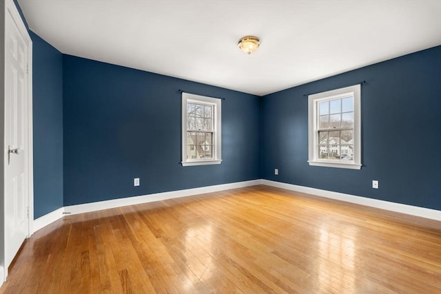 empty room with baseboards, plenty of natural light, and hardwood / wood-style floors