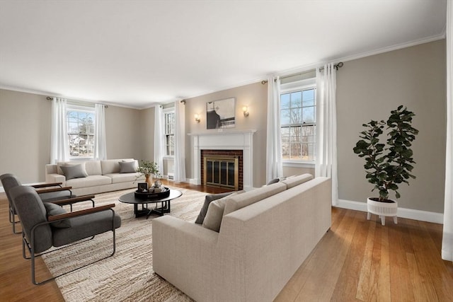 living room featuring plenty of natural light, ornamental molding, a fireplace, and wood finished floors