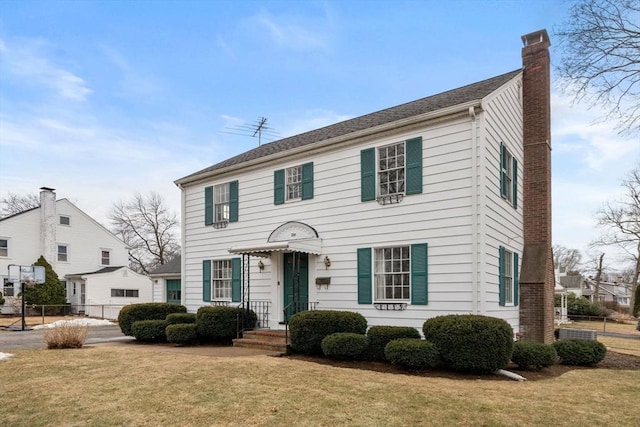 colonial-style house with a chimney and a front lawn