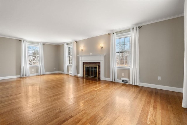 unfurnished living room with visible vents, ornamental molding, light wood finished floors, baseboards, and a brick fireplace