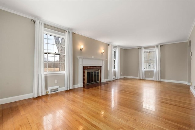 unfurnished living room with visible vents, a brick fireplace, light wood-type flooring, and crown molding