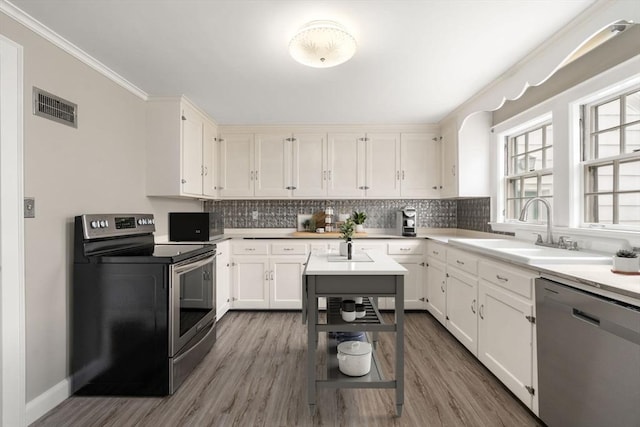 kitchen with visible vents, a sink, ornamental molding, stainless steel appliances, and backsplash