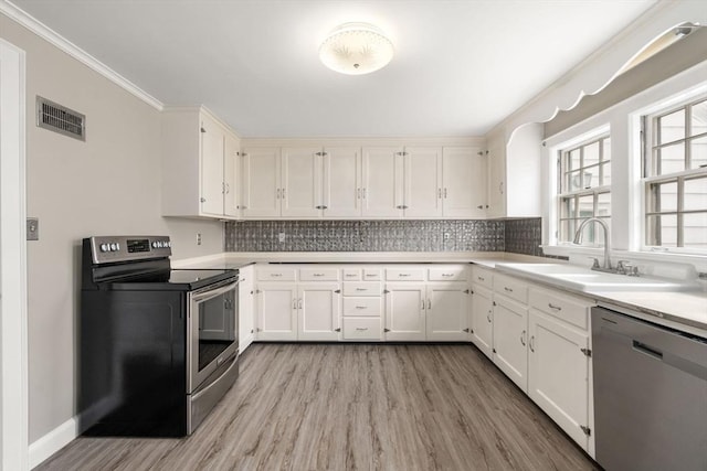 kitchen featuring visible vents, a sink, backsplash, stainless steel appliances, and crown molding