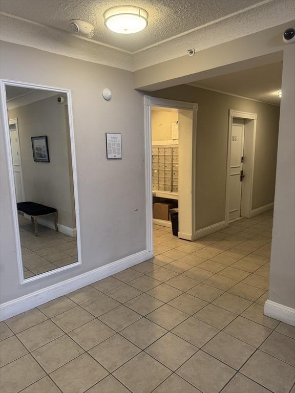 unfurnished room with baseboards, a textured ceiling, and light tile patterned flooring
