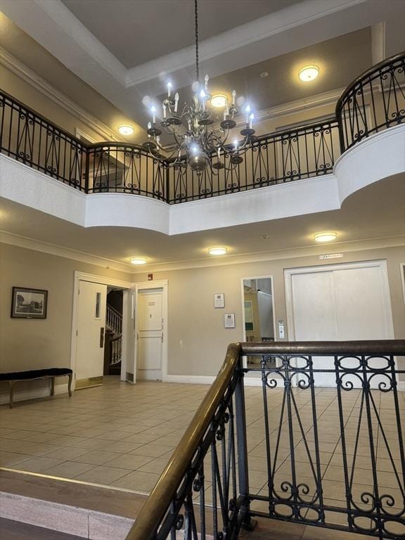 staircase with a towering ceiling, crown molding, tile patterned floors, a raised ceiling, and baseboards