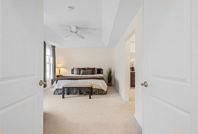 carpeted bedroom with ceiling fan and a raised ceiling