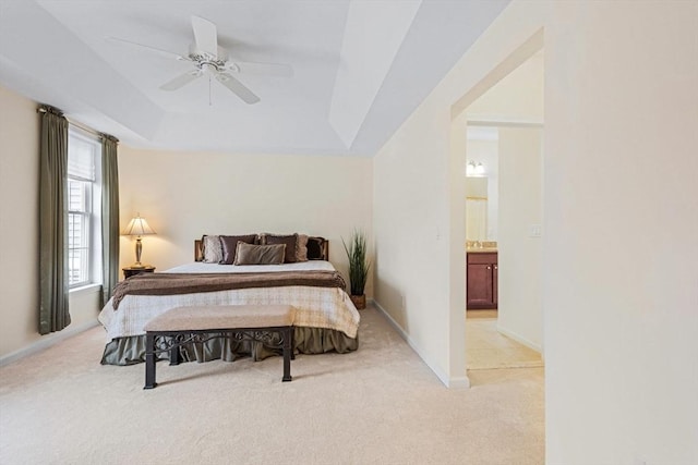 carpeted bedroom with connected bathroom, a tray ceiling, and ceiling fan