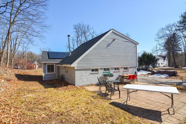 back of property with a patio area, solar panels, and roof with shingles