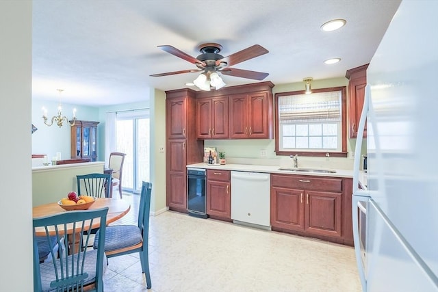 kitchen featuring sink, ceiling fan with notable chandelier, white appliances, and pendant lighting