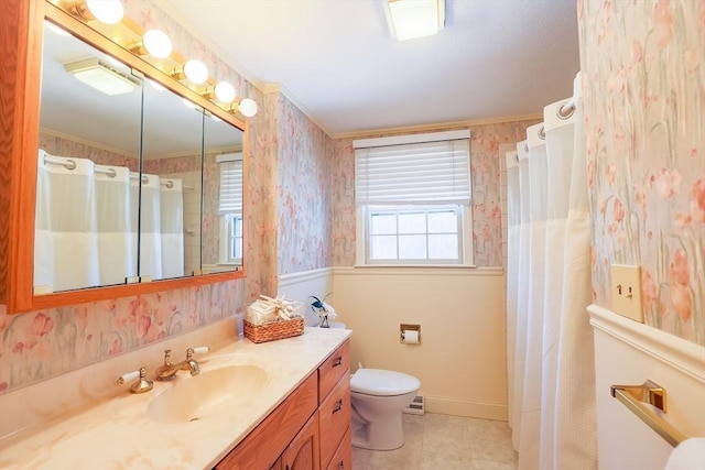 bathroom with a healthy amount of sunlight, toilet, vanity, and ornamental molding