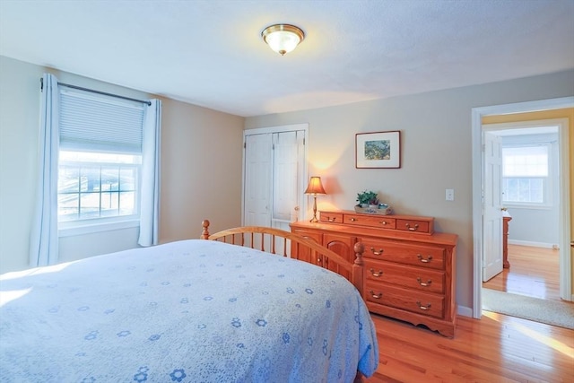 bedroom with a closet, light wood-type flooring, and multiple windows