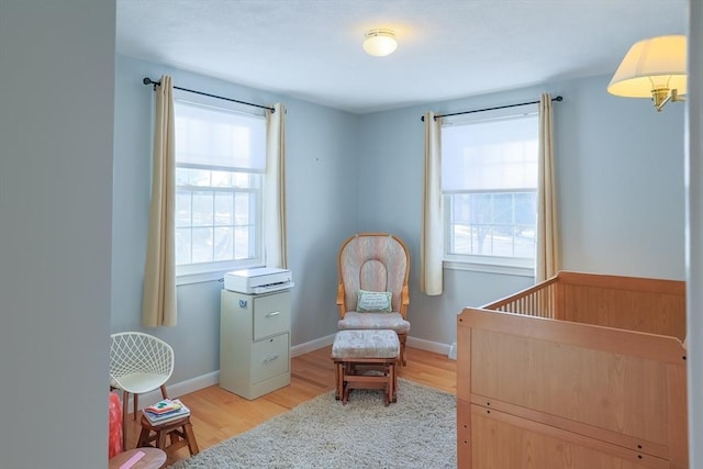 bedroom featuring multiple windows, light wood-type flooring, and a nursery area