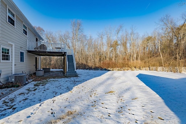 yard layered in snow with a deck and central AC unit