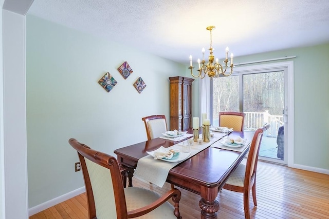 dining room featuring a notable chandelier, light hardwood / wood-style floors, and a textured ceiling