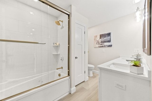 full bathroom featuring shower / bath combination with glass door, toilet, vanity, and hardwood / wood-style flooring