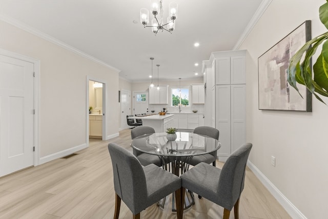 dining room featuring ornamental molding, sink, a chandelier, and light hardwood / wood-style floors