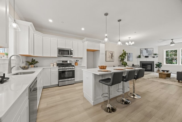 kitchen featuring white cabinets, light wood-type flooring, sink, stainless steel appliances, and ceiling fan with notable chandelier