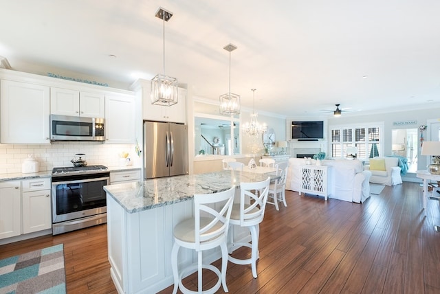 kitchen with decorative light fixtures, white cabinetry, appliances with stainless steel finishes, dark hardwood / wood-style floors, and ceiling fan with notable chandelier