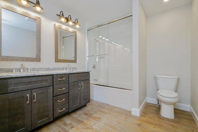 full bathroom with bath / shower combo with glass door, vanity, hardwood / wood-style floors, and toilet