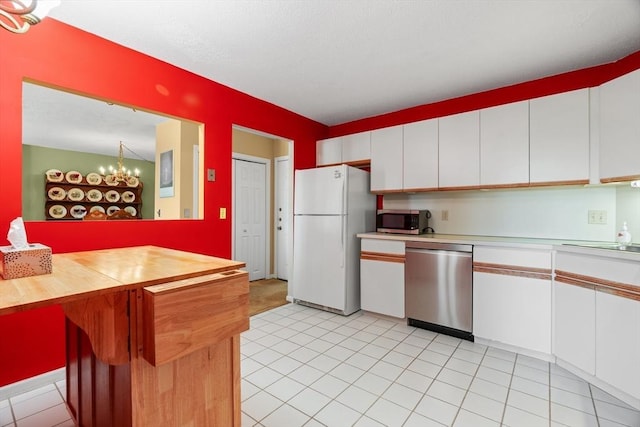 kitchen featuring appliances with stainless steel finishes, white cabinetry, a chandelier, light tile patterned floors, and wooden counters