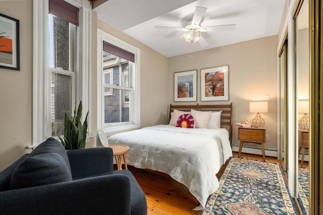 bedroom featuring a baseboard heating unit, a ceiling fan, baseboard heating, and wood finished floors