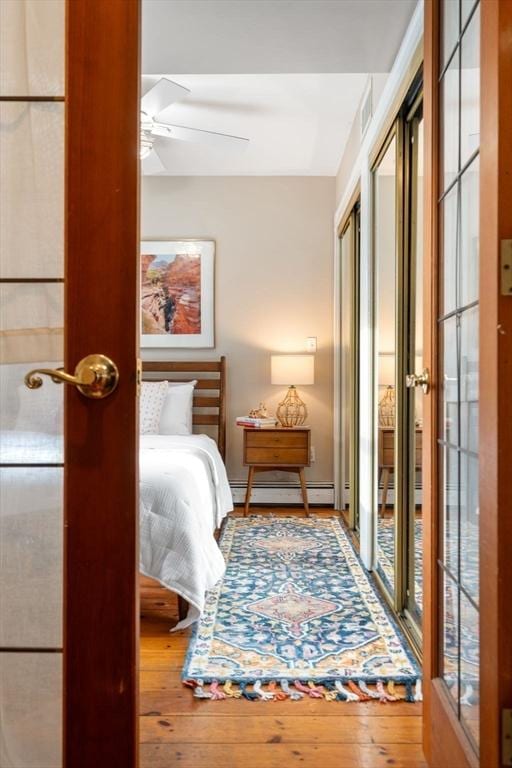 bedroom featuring hardwood / wood-style flooring, multiple windows, and a baseboard heating unit