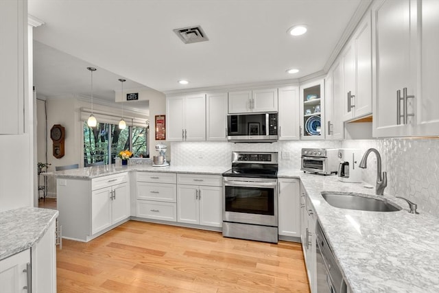 kitchen featuring visible vents, a sink, white cabinetry, a peninsula, and stainless steel appliances