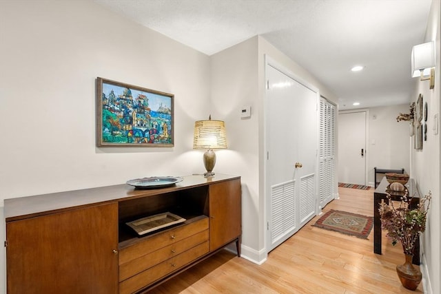 hall featuring light wood-type flooring, baseboards, and recessed lighting
