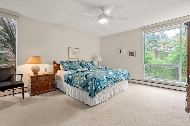 carpeted bedroom featuring baseboard heating, multiple windows, and a ceiling fan