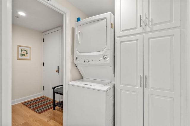 laundry room featuring laundry area, stacked washer / drying machine, light wood-type flooring, recessed lighting, and baseboards
