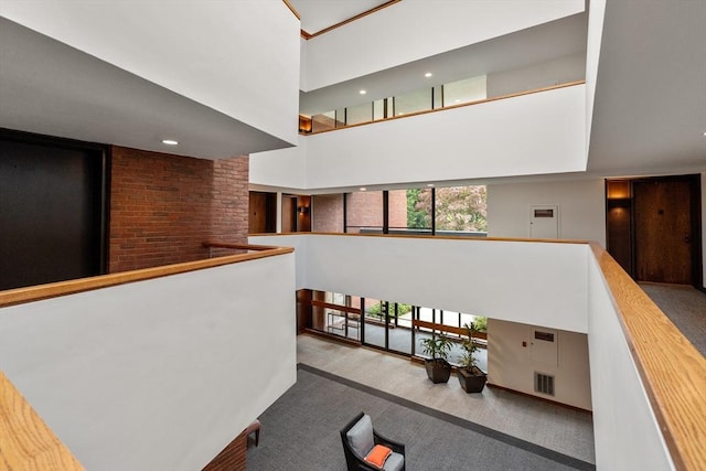 hall with a high ceiling, carpet floors, an upstairs landing, and visible vents