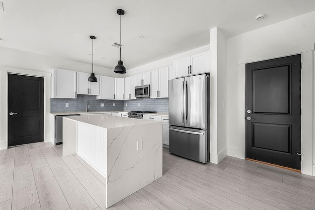 kitchen with tasteful backsplash, light wood-style flooring, stainless steel appliances, and a center island