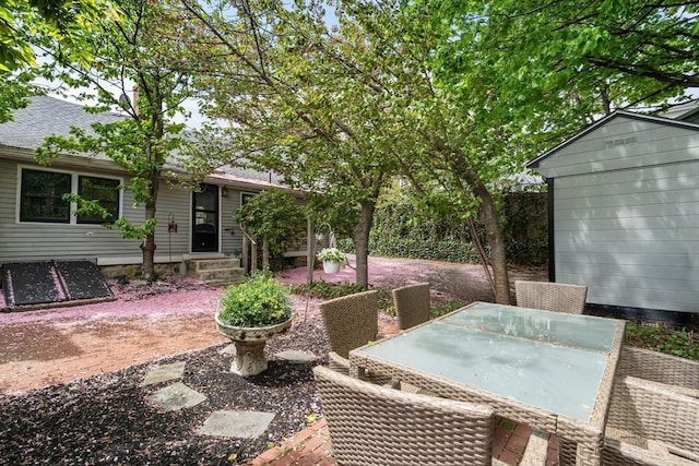 view of patio featuring outdoor dining area, entry steps, an outdoor structure, and a storage shed