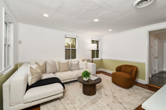 living area with wood finished floors, recessed lighting, baseboards, and a textured ceiling