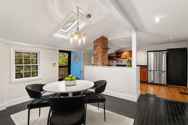 dining area with a skylight, hardwood / wood-style floors, lofted ceiling, and baseboards