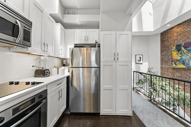 265 Beacon St Unit 5, Boston, MA 02116 - kitchen with stainless steel appliances, light countertops, dark wood-type flooring, white cabinets, and brick wall