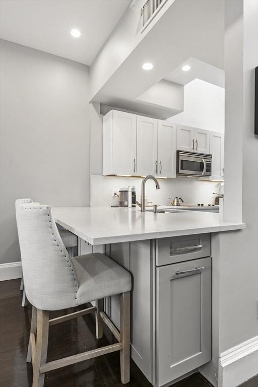 265 Beacon St Unit 5, Boston, MA 02116 - kitchen with stainless steel microwave, light countertops, a peninsula, baseboards, and a breakfast bar area