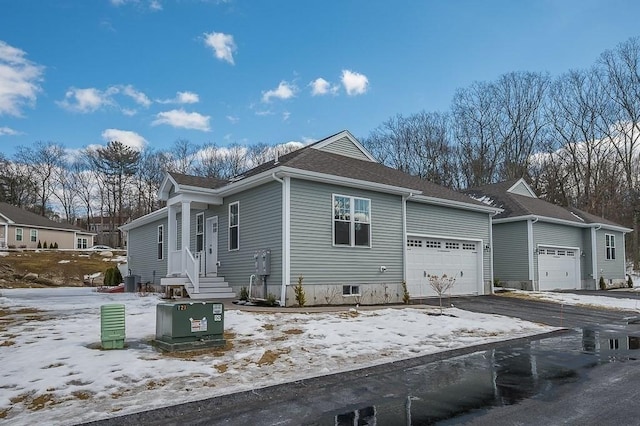 snow covered property featuring a garage and driveway