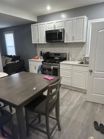 kitchen featuring decorative backsplash, white cabinetry, and stainless steel appliances