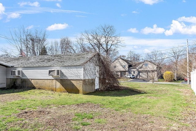 view of side of property featuring a wall unit AC and a yard